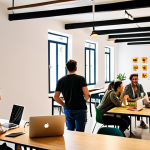 A vibrant and bustling coworking space in Lisbon, Portugal. Capture the diverse group of professionals working on laptops, collaborating at tables, and engaging in casual conversations. The space is filled with natural light, plants, and modern furniture. In the background, a startup team brainstorms ideas on a whiteboard. The overall atmosphere is energetic, innovative, and distinctly Portuguese.